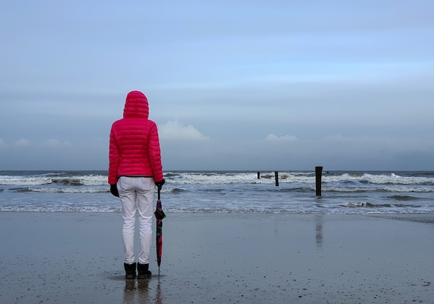 Persone che camminano in riva al mare sotto il cielo nuvoloso