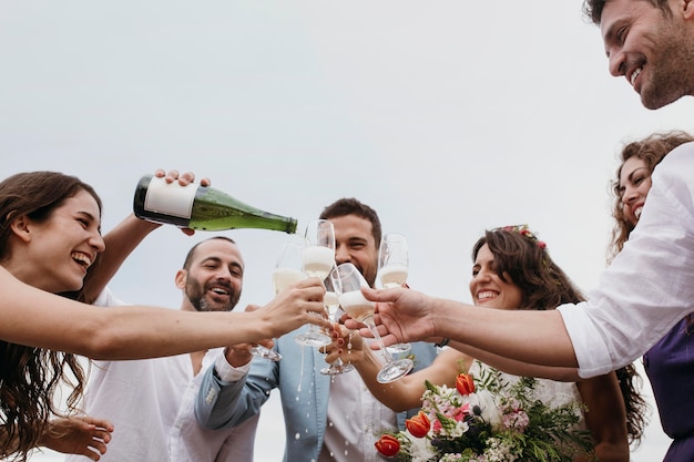 Persone che festeggiano con i loro amici che si sposano sulla spiaggia