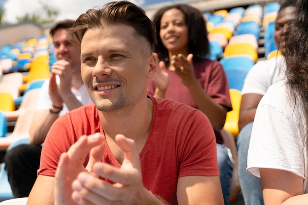 Persone che guardano insieme una partita di calcio in una giornata di sole