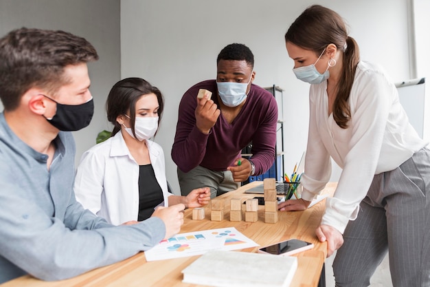 Persone che hanno una riunione in ufficio con le maschere durante la pandemia