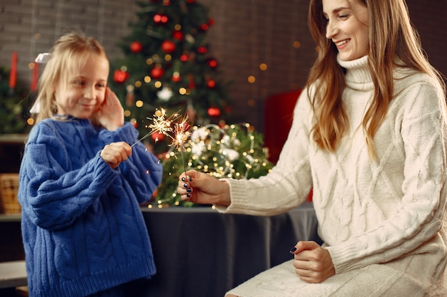 Persone che riparano per Natale. Capretto con luci bengala. La famiglia sta riposando in una stanza festiva. Bambino in un maglione blu.