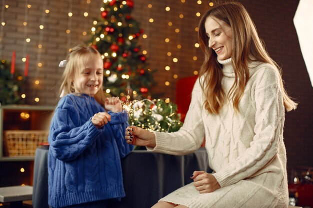 Persone che riparano per Natale. Capretto con luci bengala. La famiglia sta riposando in una stanza festiva. Bambino in un maglione blu.