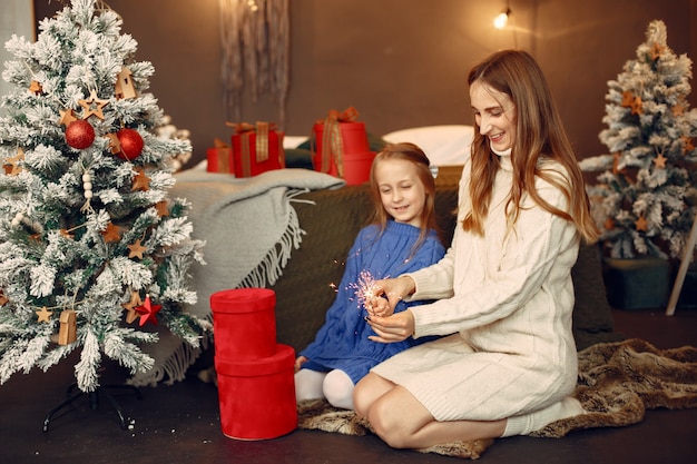 Persone che riparano per Natale. Capretto con luci bengala. La famiglia sta riposando in una stanza festiva. Bambino in un maglione blu.