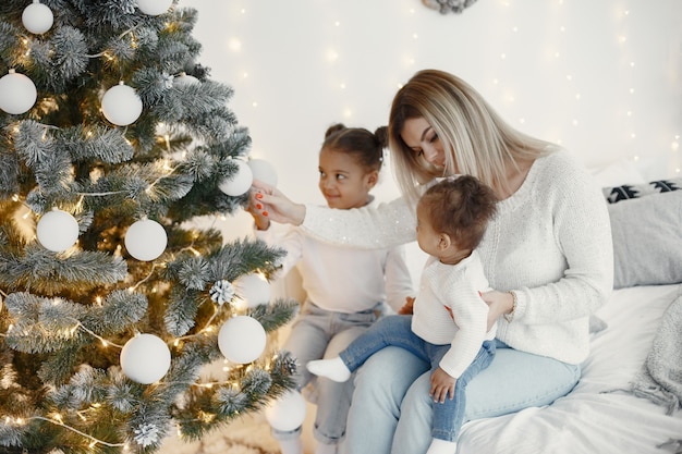 Persone che riparano per Natale. Madre che gioca con le sue figlie. La famiglia sta riposando in una stanza festiva. Bambino in un maglione maglione.