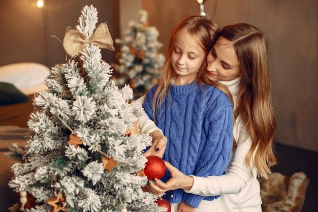 Persone che riparano per Natale. Madre che gioca con sua figlia. La famiglia sta riposando in una stanza festiva. Bambino in un maglione blu.