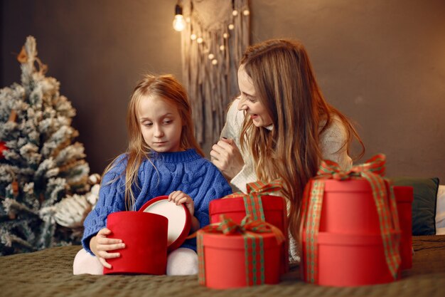 Persone che riparano per Natale. Madre che gioca con sua figlia. La famiglia sta riposando in una stanza festiva. Bambino in un maglione blu.