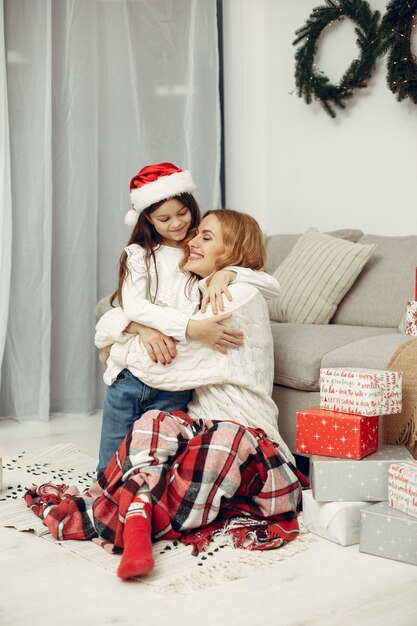 Persone che riparano per Natale. Madre che gioca con sua figlia. La famiglia sta riposando in una stanza festiva. Bambino in un maglione rosso.