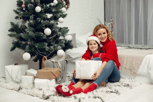 Persone che riparano per Natale. Madre che gioca con sua figlia. La famiglia sta riposando in una stanza festiva. Bambino in un maglione rosso.