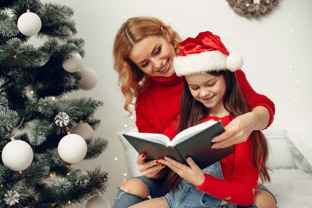 Persone che riparano per Natale. Madre che gioca con sua figlia. La famiglia sta riposando in una stanza festiva. Bambino in un maglione rosso.