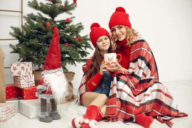 Persone che riparano per Natale. Madre che gioca con sua figlia. La famiglia sta riposando in una stanza festiva. Bambino in un maglione rosso.