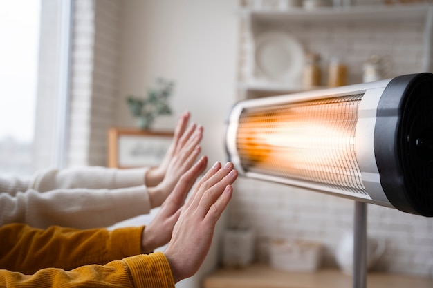 Persone che scaldano le mani vicino al riscaldatore