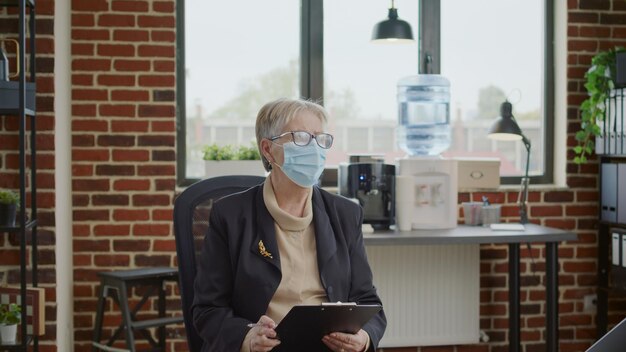Persone con dipendenza che arrivano a una sessione di terapia con uno psicologo durante la pandemia. Terapista della donna con la maschera facciale che saluta i pazienti in cerchio al programma di riabilitazione.