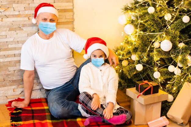 Persone con regali che indossano maschere facciali durante il coronavirus e l'epidemia di influenza a Natale. Protezione da virus e malattie, quarantena domestica. COVID-2019.