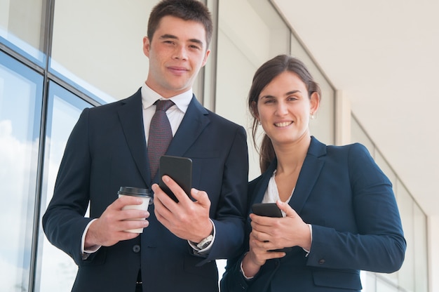 Persone di affari fiduciose allegre con gli smartphone