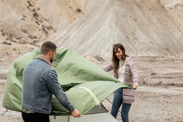 Persone di tiro medio che montano una tenda