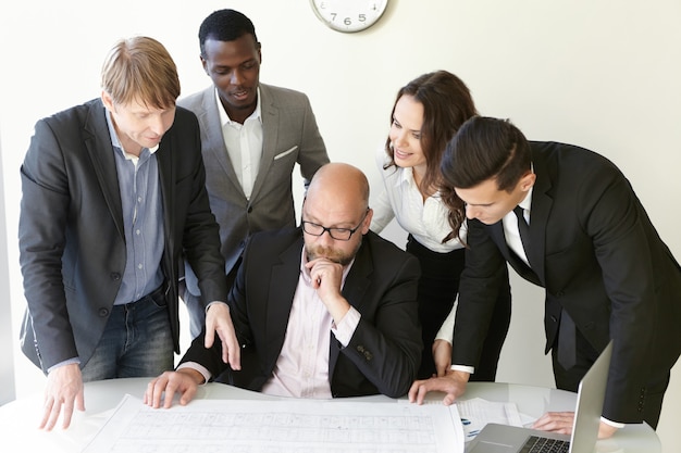 Persone e concetto di lavoro di squadra. Gruppo di ingegneri che lavorano insieme sul piano di nuova costruzione durante la sessione di brainstorming.