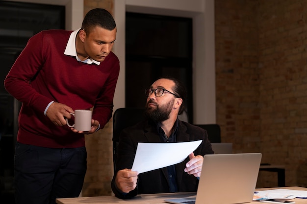 Persone esauste in ufficio che lavorano fino a tardi