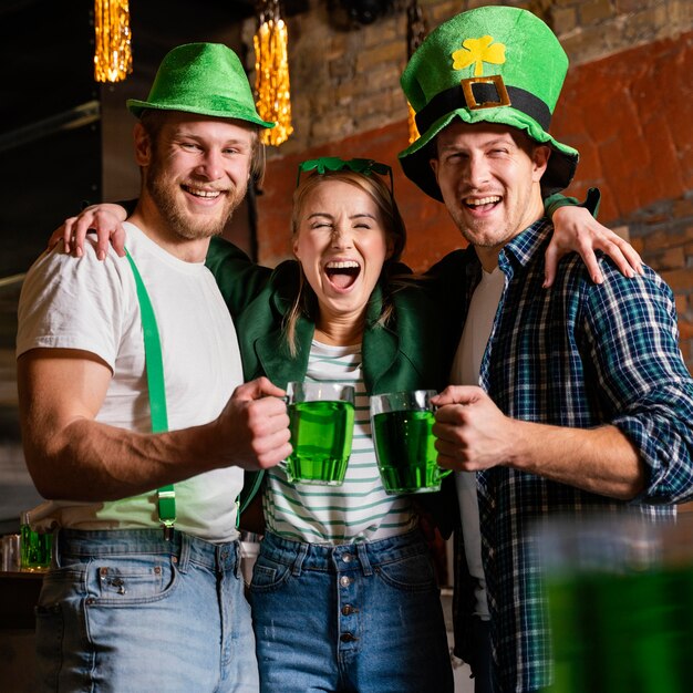 Persone felici che celebrano st. patrick's day al bar con bevande