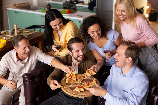 Persone felici di tiro medio che mangiano pizza