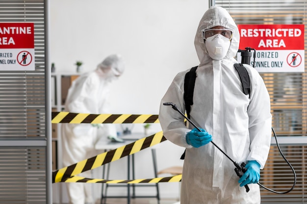 Persone in equipaggiamento protettivo che disinfettano un'area pericolosa