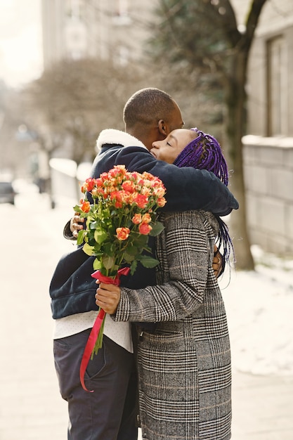 Persone in piedi fuori. L'uomo regala fiori per la femmina. Coppia africana. San Valentino.