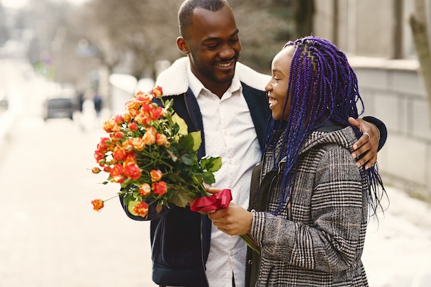 Persone in piedi fuori. L'uomo regala fiori per la femmina. Coppia africana. San Valentino.