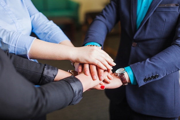 Persone in piedi in ufficio che tengono le mani insieme