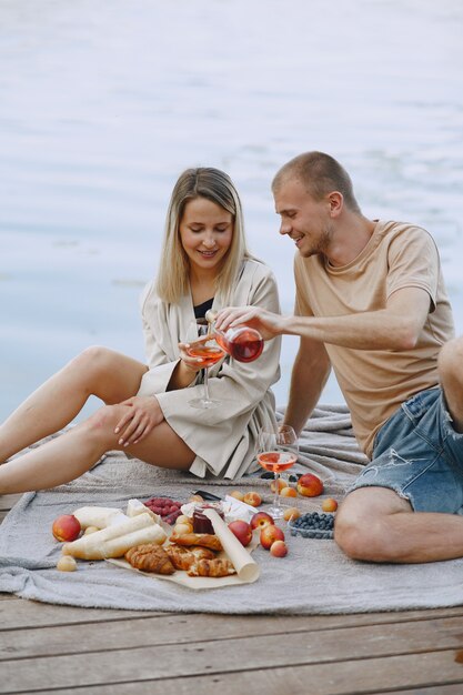 Persone in riva al fiume. Delizioso picnic estivo sano sull'erba. Frutta su un blancet.