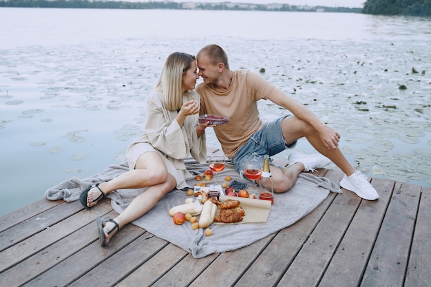 Persone in riva al fiume. Delizioso picnic estivo sano sull'erba. Frutta su un blancet.