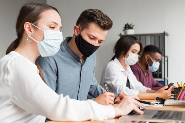 Persone in ufficio che lavorano durante una pandemia con le maschere