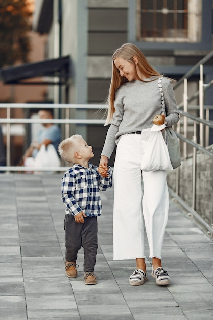 Persone in una città estiva. Madre con figlio. Donna in un maglione grigio.