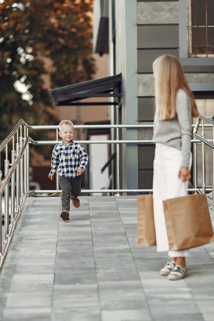 Persone in una città estiva. Madre con figlio. Donna in un maglione grigio.