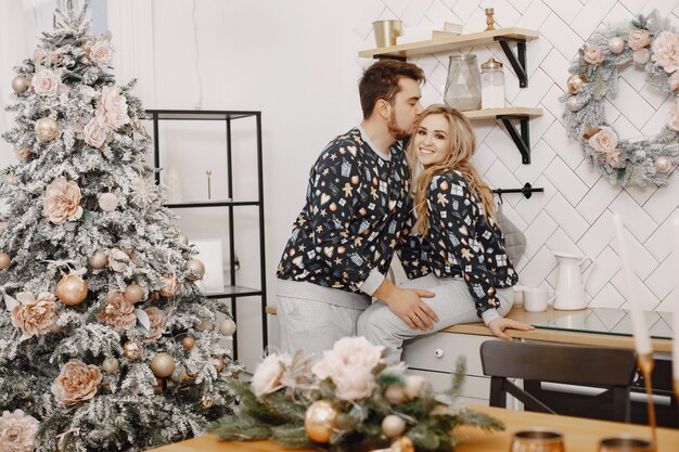 Persone in una decorazione Christman. Uomo e donna in pigiama identificativo. Famiglia in una cucina.