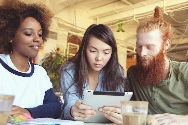 Persone, innovazioni e tecnologia. Persone di affari che studiano i dati finanziari sul pc del touch pad con sguardo concentrato.