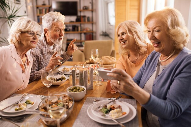 Persone mature felici che comunicano mentre pranzano insieme nella sala da pranzo di casa