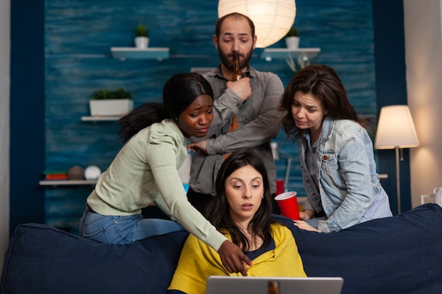 Persone multietniche che socializzano bevendo alcol parlando con un amico in videochiamata. Gruppo di persone multirazziali in teleconferenza, videochat party sul laptop durante l'intrattenimento notturno