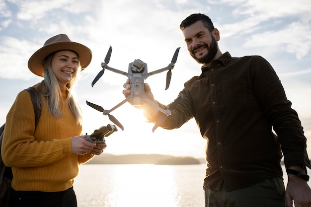 Persone sorridenti del colpo medio che tengono il drone all'aperto