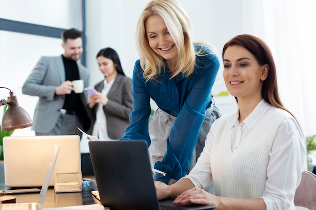 Persone sorridenti di tiro medio che chattano al lavoro