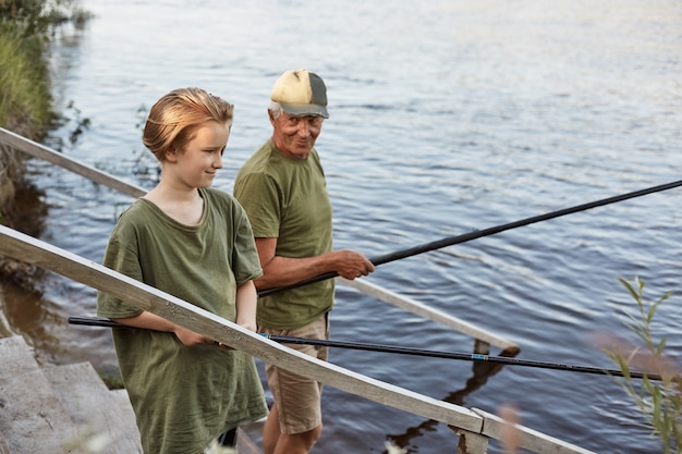 Pesca del figlio e del padre sulle scale di legno che conducono per innaffiare