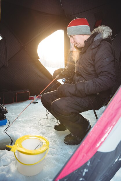 Pescatore sul ghiaccio che pesca stando seduti