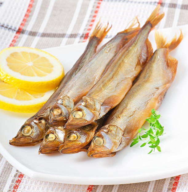 Pesce affumicato con il limone in un piatto bianco