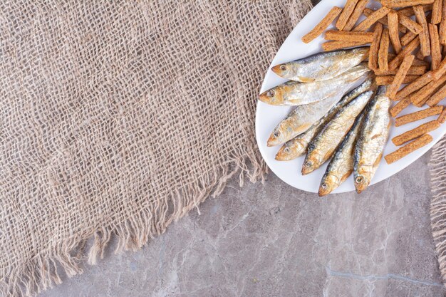 Pesce e cracker deliziosi sul piatto bianco. Foto di alta qualità