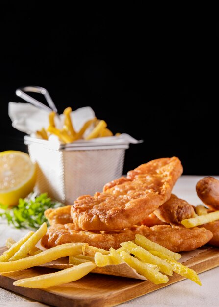 Pesce e patatine fritte sul tagliere con limone e copia spazio