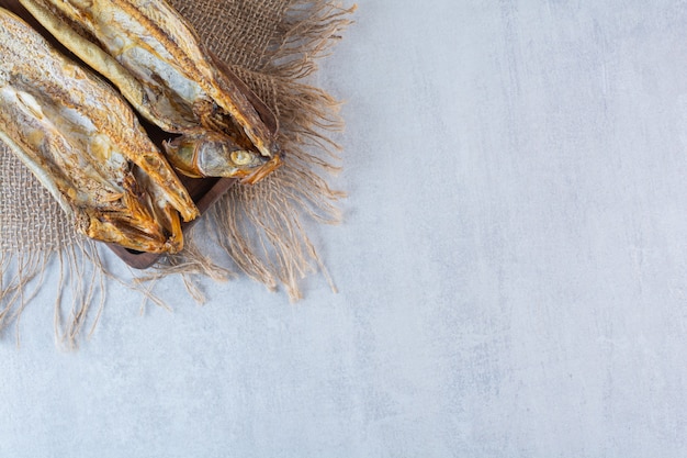 Pesce essiccato salato isolato su una tavola di legno.