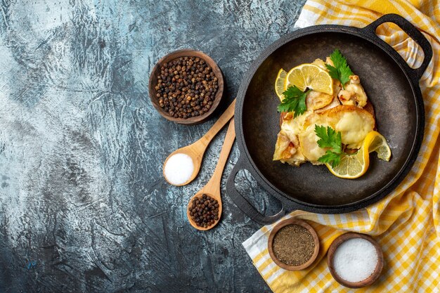 Pesce fritto vista dall'alto in padella con limone e prezzemolo su tovaglia a scacchi bianca gialla