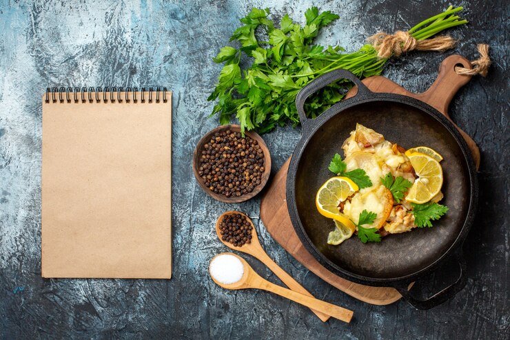 Foto gratuito pesce fritto vista dall'alto in padella con spezie di limone e prezzemolo in cucchiai di legno