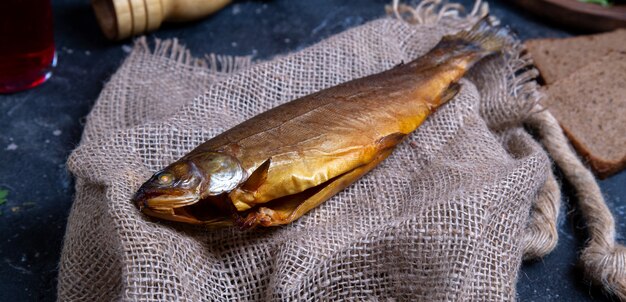 Pesce secco affumicato su un pezzo di tessuto rustico sul tavolo blu