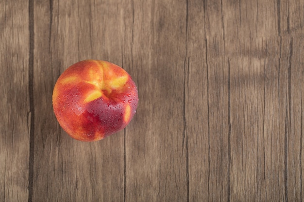 Pesche rosse isolate sulla tavola di legno.