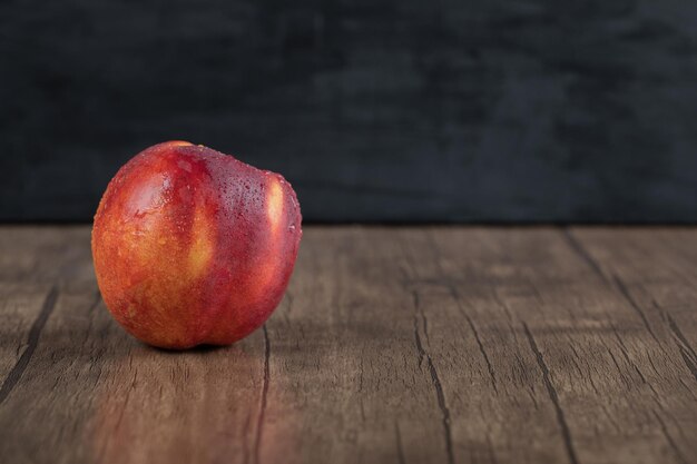 Pesche rosse isolate sulla tavola di legno.