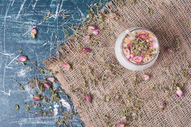 Petali di fiori con una tazza di bevanda sull'azzurro.